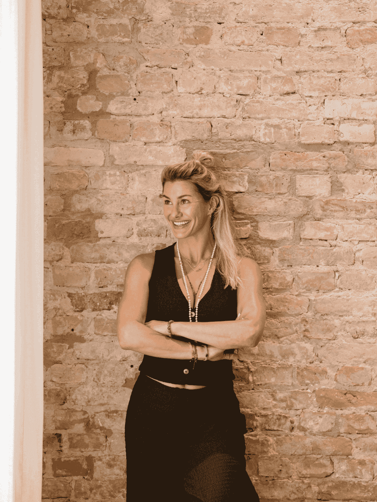 Dominique Scharax laughing in front of a brick wall